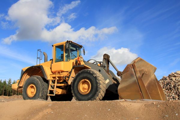 Yellow wheel loader at Sandpit against blue sky.